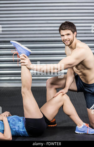 Male trainer assisting woman stretching Stock Photo