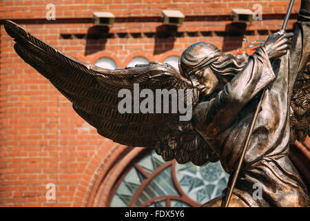 Statue Of Archangel Michael With Outstretched Wings, Thrusting Spear Into Dragon near Red Catholic Church Of St. Simon And St. H Stock Photo