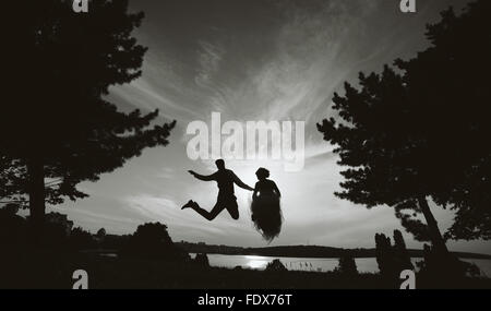 groom and bride jumping against the beautiful sky Stock Photo