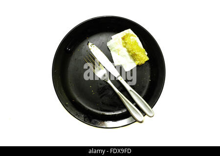 A knife and fork on an empty black plate photographed against a white background Stock Photo