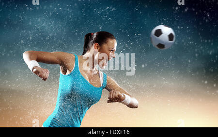 Image of young woman football player hitting ball Stock Photo