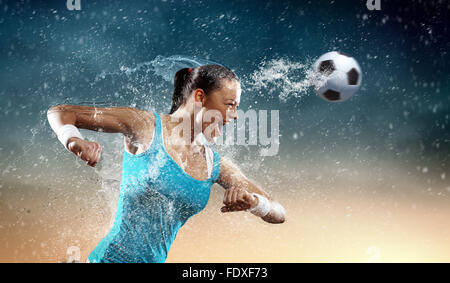 Image of young woman football player hitting ball Stock Photo