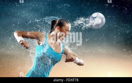 Image of young woman football player hitting ball Stock Photo