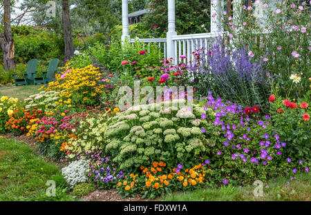 Bass Harbor, Maine: Summer cottage garden and covered porch. Flower garden features sedum 'Autumn Joy', coreopsis, rudbeckia, zi Stock Photo