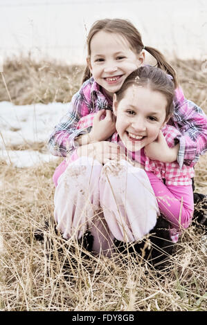 Two smiling sisters hugging in country field Stock Photo