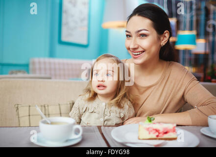 Happy woman and cute little girl sitting in cafe Stock Photo