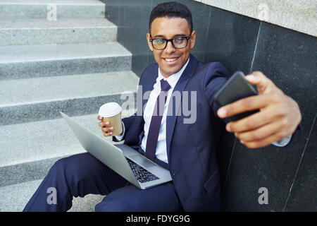 Modern businessman making selfie while sitting on stairs Stock Photo