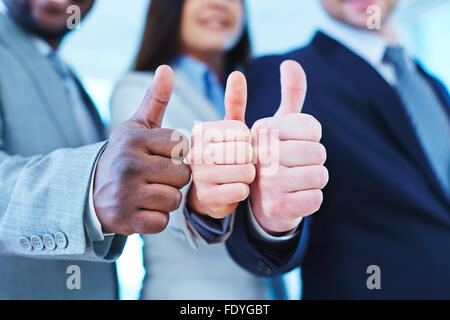 Thumb up gesture shown by three business partners Stock Photo
