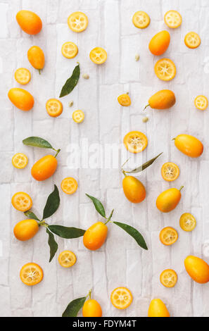 Fresh organic kumquats. Kumquats whole and sliced, still life pattern background, overhead view Stock Photo