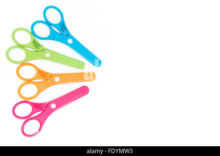 Red, orange, green, and blue plastic kids safety scissors arranged on a white background with copy space Stock Photo