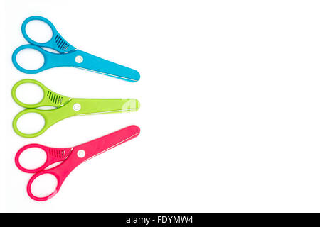 Red, green, and blue plastic kids safety scissors arranged on a white background with copy space Stock Photo