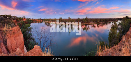 Panorama of still river water of Murray between elevated Victoria Red Cliffs and low NSW plains at sunset