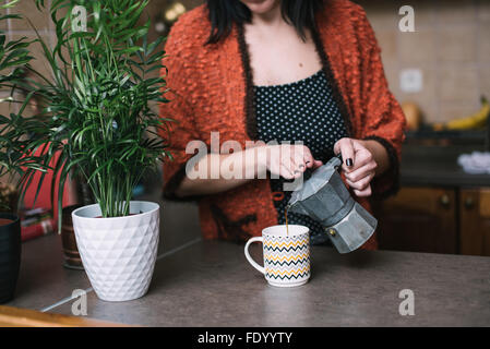 Woman in kitchen pouring coffee from vintage coffee maker Stock Photo