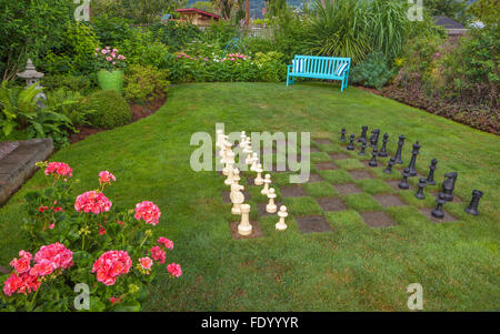 Vashon-Maury Island, WA: Over-sized chess board in a lawn with bright blue bench in a cottage garden Stock Photo