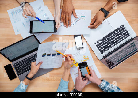 Business people using mobile phones and laptops, calculating and discussing charts and diagrams for financial report Stock Photo
