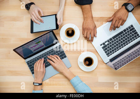 Top view of multiethnic group of young people using laptops and tablet and drinking coffee Stock Photo