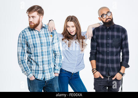 Beautiful confident young woman standing between two bearded pensive young men Stock Photo