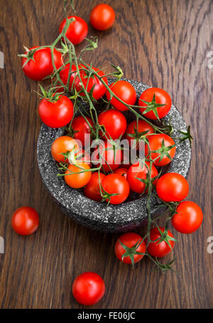 Cherry tomatoes in marble mortar on wooden table Stock Photo