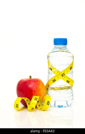 Water bottle wrapped in yellow imperial tape measure with red apple isolated on white background with copy space Stock Photo