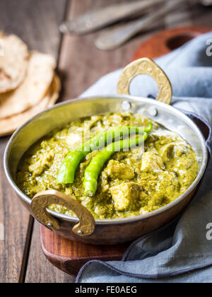 Indian cuisine: palak paneer in traditional copper bowl served with tandoori roti on a dark wooden table. Stock Photo