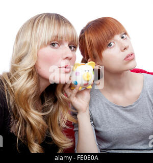 young beautiful blond and red haired girls ears on moneypig on red sofa in front of white background Stock Photo