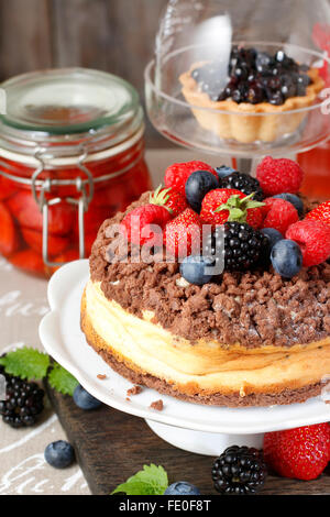 Cheesecake with chocolate topping decorated with summer fruits: raspberries, strawberries, blueberries and blackberries. Stock Photo
