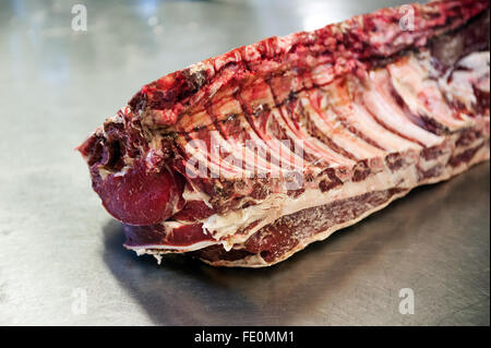 Close up of raw rib eye steak section on metal table in meat processing plant Stock Photo
