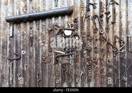 Detail of different rusty metallic bolts, screws, nuts and other parts on a metal surface background Stock Photo