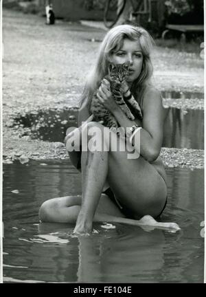 1973 - The Continuous Bad Weather Makes Inventive: After the momentary continual cloudbursts fanatic water-fans, as the student Steffi of Munich, can even a street strewn with road holes acquire a fascination for a ''bath in front of the door''. While the 19-year-old bath-nix is apparently happy, the little cat is afraid of water and remains dry in the arms of ''Wifey''. But Caution for all, who absolutely want to Paddle in the dingy water: At the bottom hidden broken bottles, rusty nails or stone can have unpleasant results. In our case Steffi took care: She lives in the neighborhood and ther Stock Photo
