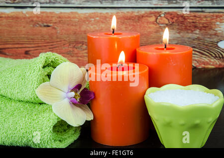 burning orange candles, mineral salt, orchid and towel still life Stock Photo