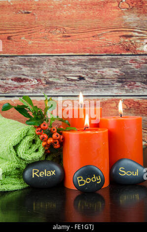 burning orange candles,orange berry, lava stones and green towel still life Stock Photo