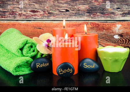 burning orange candles,orchid lava stone and towel still life Stock Photo