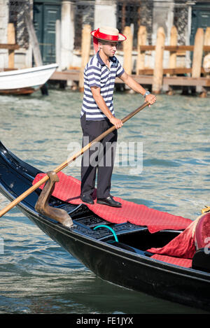 A gondolier wearing his blue & white striped shirt and boater with a blue band in Venice, northern Italy Stock Photo