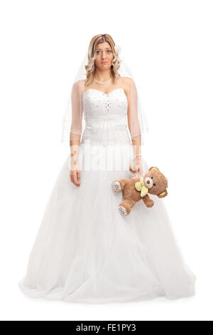 Full length portrait of a young sad bride holding a teddy bear and looking at the camera isolated on white background Stock Photo