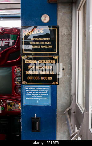 Colourful warning notices attached to a pillar at an entrance to the amusements arcade on Paignton Pier Stock Photo