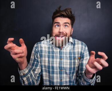 Portrait of ugly bearded young man in checkered shirt grimacing over black background Stock Photo
