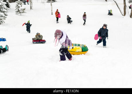 UFA - RUSSIA 16TH JANUARY 2016 - Children enjoy the fresh snow by using improvised slides and sleds to slide down snow banks in Stock Photo