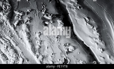 Fresh patterns in winter snow create abstract shapes and forms with natural sunlight creating areas of contrast amongst the peak Stock Photo