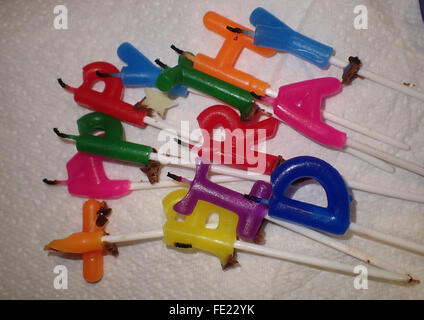 Used multicoloured birthday cake candles spelling out 'HAPPY BIRTHDAY' on white paper towel Stock Photo