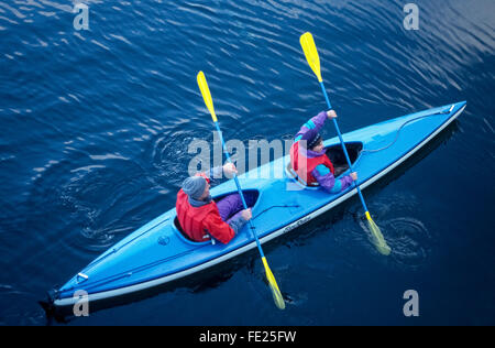 Two visitors in colorful jackets and life vests paddle in a kayak in Takatz Bay off Baranof Island along the Inside Passage in Alaska, USA. Stock Photo