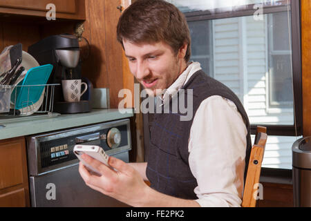 Blind man in his kitchen listening to assistive technology on his cell phone Stock Photo