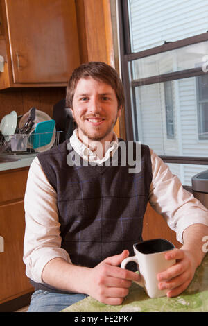 Young blind man sitting in his kitchen with a cup of coffee Stock Photo