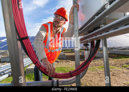 Solar photovoltaic installer working on power connections for a PV array Stock Photo