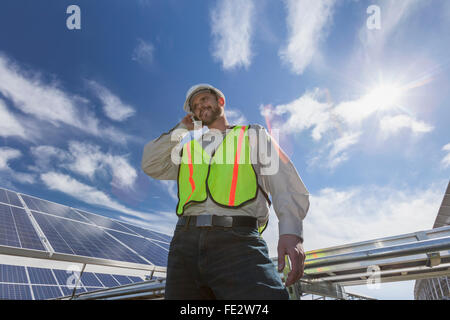 Power engineer talking on cell phone in front of solar photovoltaic array Stock Photo