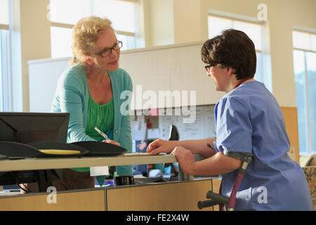 Nurse with Cerebral Palsy checking with administration about a patient's records in a clinic Stock Photo