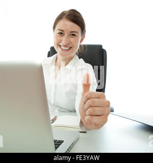 young brunette business woman shows thumb up on desk with a laptop Stock Photo