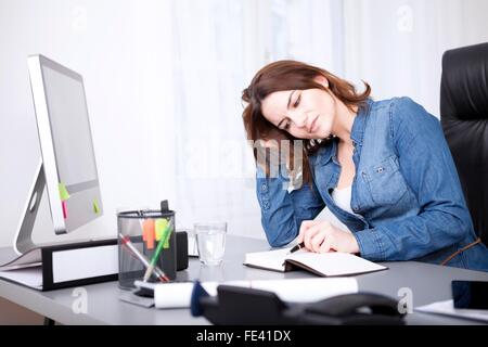 Close up Young Adult Businesswoman in Denim Shirt Reading a Book with Pen While Leaning at the Table Stock Photo