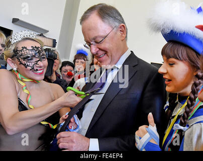 Hanover, Germany. 04th Feb, 2016. Carnival enthusiast Susan from Linden, Germany (L), cuts off the tie of Stephan Weil (C), premier of the German state Lower Saxony, in his office at the State Chancellery in Hanover, Germany, 04 February 2016. Photo: HOLGER HOLLEMANN/dpa/Alamy Live News Stock Photo
