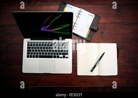 Macbook on table with Moleskin notebook and leather bound diary Stock Photo