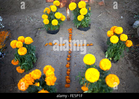 A cross made with yellow marigold flowers, known as cempasuchil, decorate a tomb at the cemetery in San Gregorio Atlapulco Stock Photo